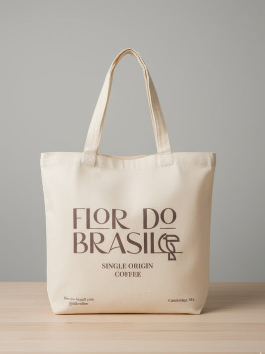 A simple, flat tote bag made of natural-colored cotton, featuring the Flor do Brasil minimalist logo